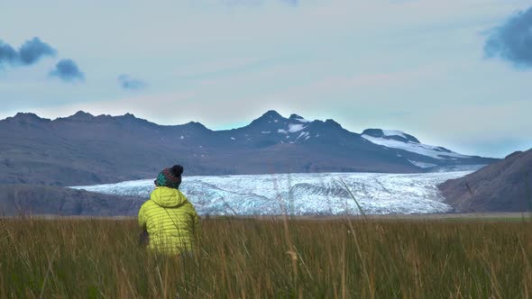 A Woman Sits in the Grass and Enjoys the Beautiful Nature of Iceland