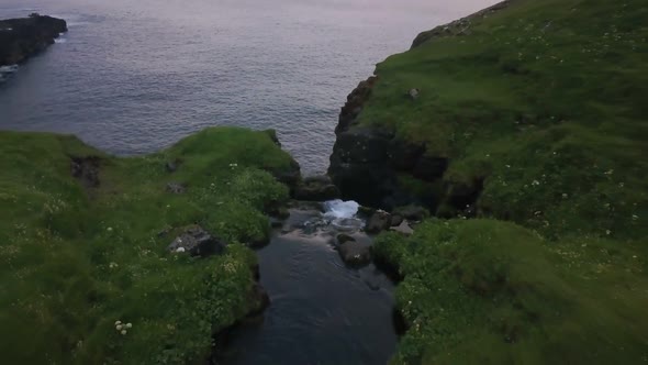 Small Waterfall Falls Into the Sea From the Cliffs