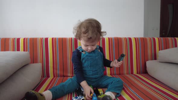 Cute little kid playing with toys on the sofa at home. Home activities. Childhood