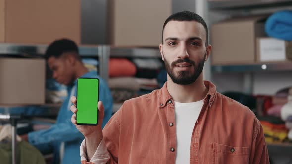 Portrait View of the Caucasian Man Holding Smartphone with Green Mock Up Screen and Showing It to