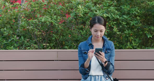 Woman read on smart phone and sit on the bench