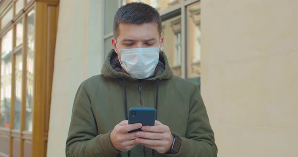 Man Wearing Protective Face Mask Use Phone. COVID-19 Coronavirus Infection. Portrait of a Caucasian
