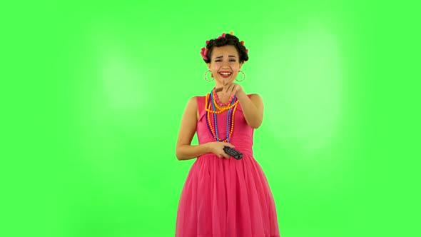 Woman with TV Remote in Her Hand, Switching on TV and Very Laughs. Green Screen