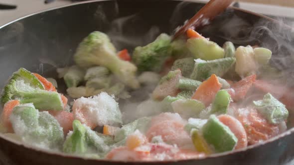 Frozen Vegetables are Cooked in a Frying Pan Highlighting Steam