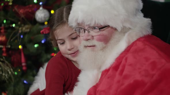 Santa Clause hugs young girl and gives her a candy cane