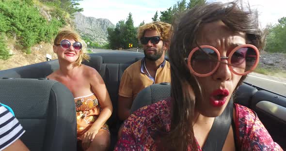 Beautiful young woman having fun driving her friends in convertible