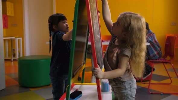 Cute Diverse Girls Drawing on Easel Board at Class