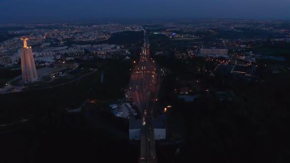 Night Aerial View of Busy Multi Lane Highway and Santuario De Cristo Rei White Monument on the Coast