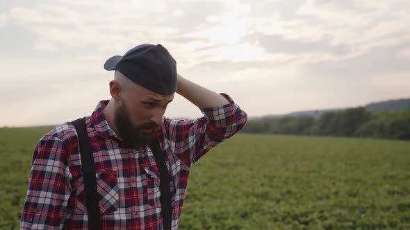 Tired Man Wipes His Sweaty Forehed on Green Field