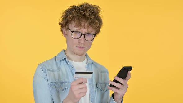 Online Shopping on Smartphone By Redhead Young Man, Yellow Background 