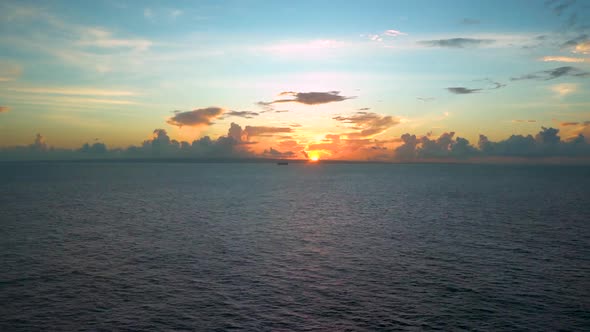 Spectacular timelapse view of the sun rising from beyond the Caribbean horizon, blue sky above, clou