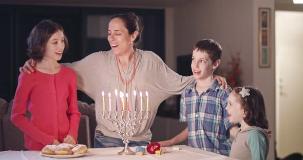 Kids and their mother lighting Hanukka candles