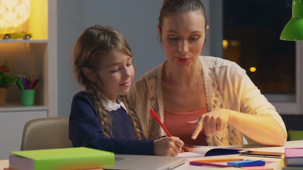 Young Mother Hepling Her Daughter with Homework