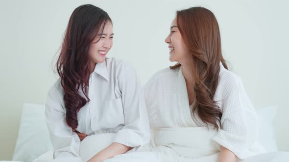 Portrait of Asian beautiful lesbian woman couple sit on bed at home.