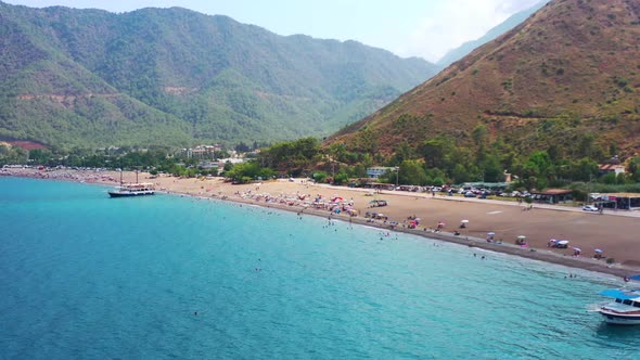 aerial drone reveling the blue Mediterranean coastline of Adrasan Beach full of tourists and a dry m