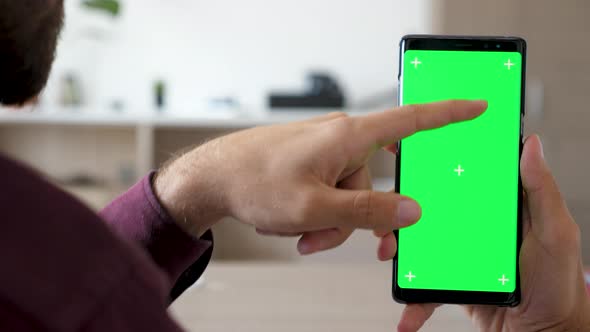 Close Up of Man Hand Touching and Using a Smartphone with Green Screen Chroma Mock Up on It