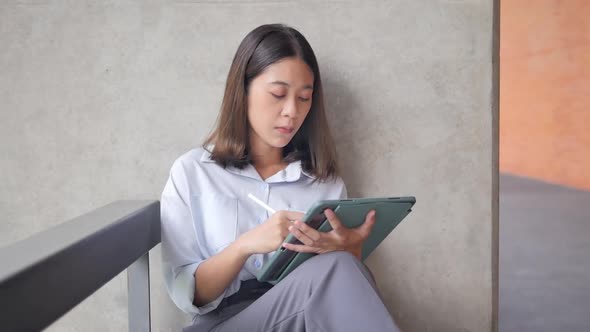 A female freelancer interacts with a tablet display using a stylus using a touch