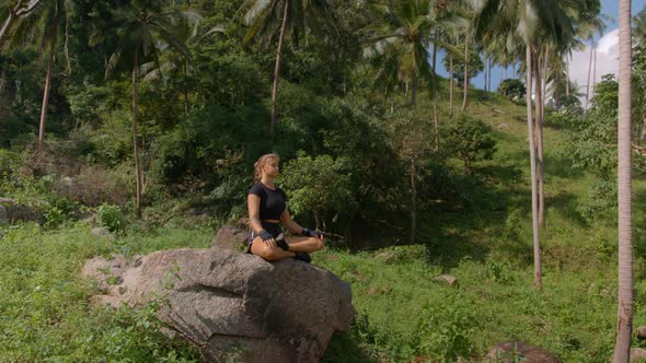 Young Pretty Woman Doing Yoga Exercise on Big Rock in the Tropical Rain Forest Meditation Concept