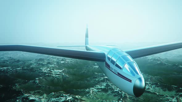 The white sailplane calmly gliding in the sky over the snow-covered mountains.