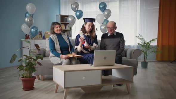 Family with Their Graduate Daughter Holding Diploma Celebrate Graduation From University at Home