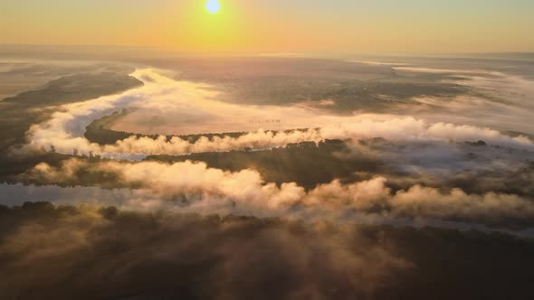 Aerial drone view of nature of Moldova at sunset. River and lush fog above it, village, greenery
