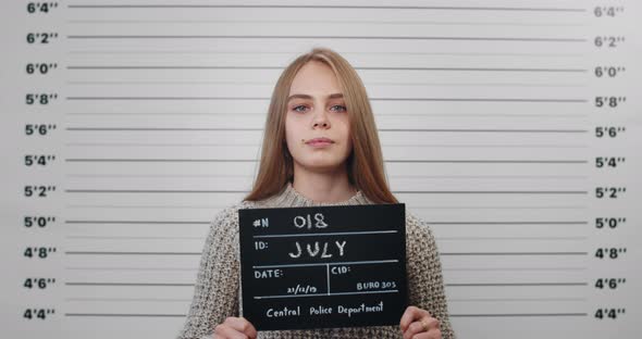 Portrait of Young Woman with Long Blond Hair Holding Sign for Photo in Police Department
