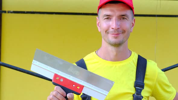 Portrait of a house repair and construction master with a close-up tool. A builder with a spatula in