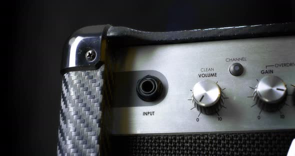 Musician Turns on the Combo Amplifier for Electric Guitar on Black Background