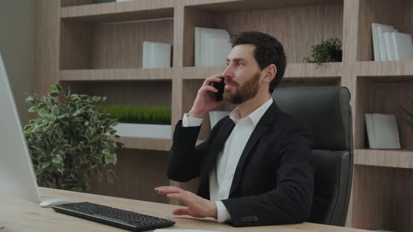 Goodlooking Employee Indoors at His Workplace Talking Positively on the Phone