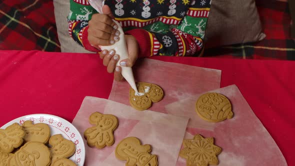 Little African American Girl Wearing Christmas Print Sweater Is Icing Traditional Christmas Cookies