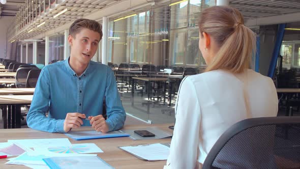 Employee Sitting at the Desk Opposite Client