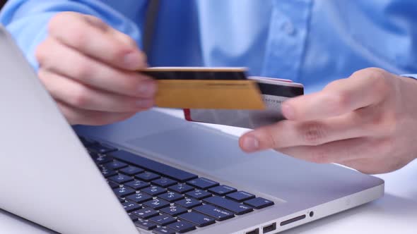 Online Shopping. Laptop. Man Typing on a Laptop While Holding a Credit Card. Close Up