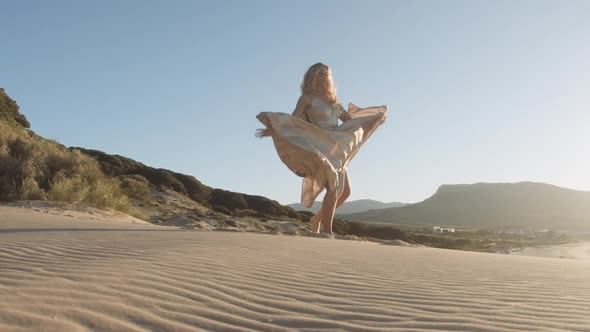 Blond Woman In Gold Dress Dancing On Beach