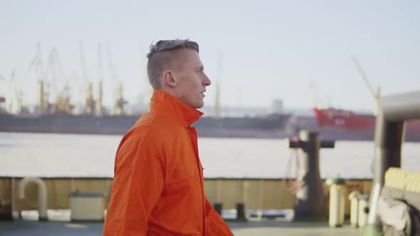 Harbor Worker in Orange Uniform is Walking on Cargo Harbor Site