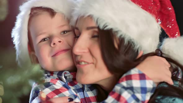 Happy Family Mother and Cute Little Son Hugging and Smiling Together Near Christmas Tree Closeup