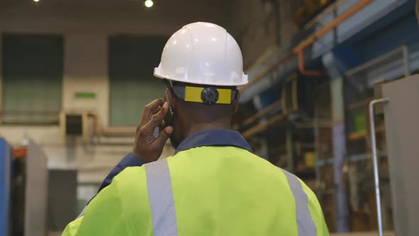 African Factory Worker Having Phone Call Walking in Plant