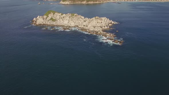 Aerial View of a Beautiful Small Rocky Island Surrounded By Clear Blue Sea