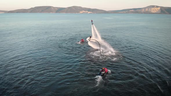 People Flying on Jet Packs Over Water