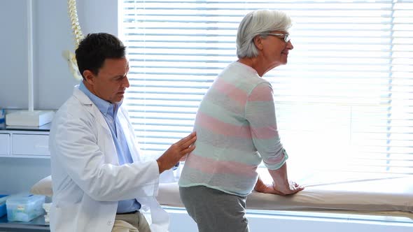 Physiotherapist giving back massage to senior patient