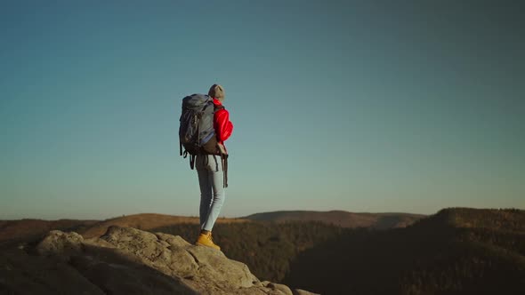 Slow Motion View From Behind Adventurous Female Hiker Backpacker in Red Jacket with Backpack Stands