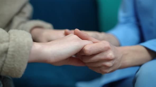 Closeup Caucasian Women Holding Hands Sitting on Sofa Indoors