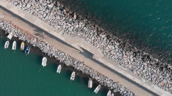 Stone walking path to lighthouse with moored boats, top view