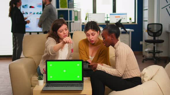 Businesswomen Discussing in Back of Laptop with Greenscreen