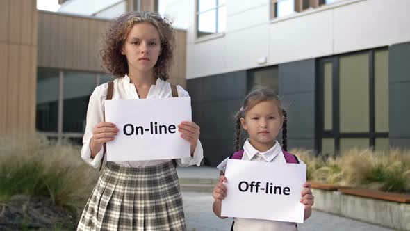 Two Schoolgirls with Placards are Standing in Front of the School Building