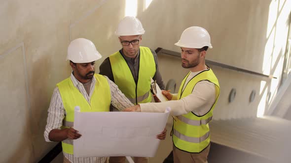 Architects in Helmets with Blueprint at Office