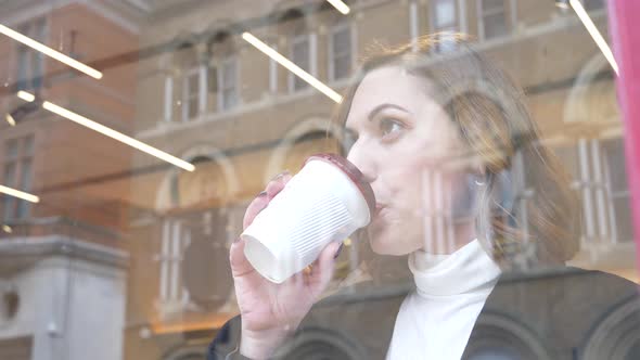 Slow motion shot of young woman drinking coffee in a cafe