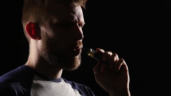 Guy Smokes an Electronic Cigarette and Exhales a Lot of Smoke, Black Background