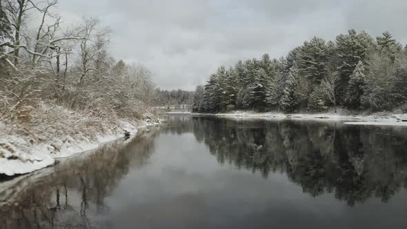 Flying along snowy banks of Piscataquis river. Maine. USA. Aerial