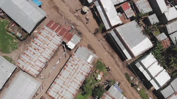 Aerial drone shot of a main road full of humble houses overlooking the rooftops. Man walking through