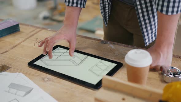 Male Carpenter Looking at Technical Drawings of Furniture on Tablet Screen